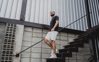 A young man in t-shirt and shorts on the stairs at city streets