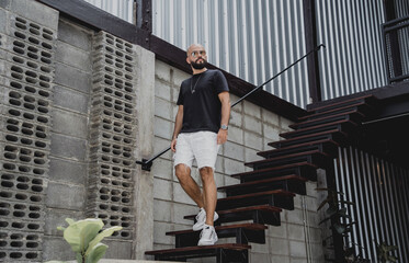 A young man in t-shirt and shorts on the stairs at city streets