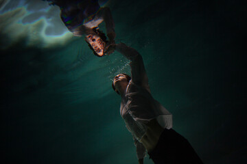 underwater shooting with contrasting light, a guy is swimming underwater, pulling his hand to his...