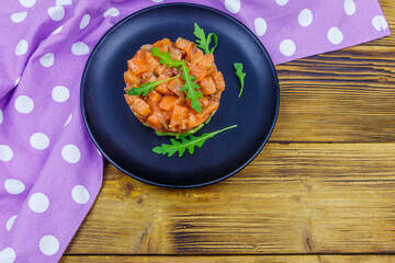 Salmon tartare with avocado and arugula on wooden table. Top view