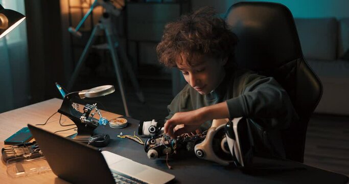 Portrait of a boy spending time in room at desk, repairing a robot, screwing in screws to improve the operation of a toy, passionate about mechanics, electronics, robotics.