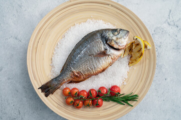 Top view of plate with fresh grilled dorado fish with lemon and tomato