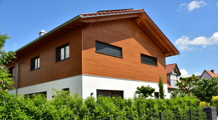 Modernes Holzhaus in Ständerbauweise mit Fassadenverkleidung aus lasiertem Nadelholz, alpine Architektur - obrazy, fototapety, plakaty