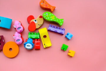 Child is playing with colorful wooden and plastic toys, on pink background