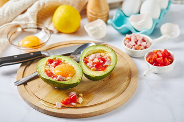 Avocado with egg, ham, tomatoes and cheese. Keto lunch recipe. Before baking