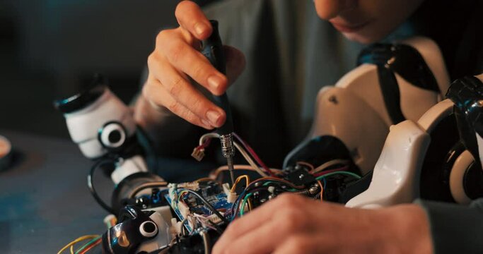A portrait of a smiling boy, the talented intelligent student prepares a robot for the school competition, twists screws, assembles a toy from scratch.