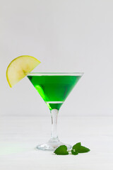 martini with lime.Apple cocktail mixed drink with vodka and apple slice. Apple martini cocktail on the white table. Green Alcoholic drinks in martini glasses with apple slice. copy space. vertical