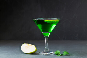 Apple cocktail mixed drink with vodka and apple slice. Apple martini cocktail on the black background. Green Alcoholic drinks in martini glasses with apple slice. copy space.