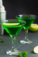 martini with mint.Apple cocktail mixed drink with vodka and apple slice. Apple martini cocktail on the black background. Green Alcoholic drinks in martini glasses with apple slice.