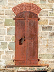Old rusted door with a stone wall surrounding