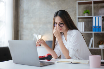 Beautiful woman is study and working on paperworks and laptop at home.