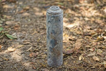 one old gray metal burnt deodorant spray bottle stands on brown ground in the street