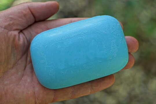 One Blue Bar Of Soap Lies On The Palm Of The Hand On A Green Background