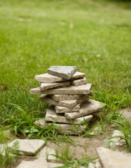 Cairn of stones on a green grassy lawn. Stone tiles and lawn.