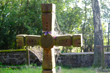 Old wooden cross with spider's web lit by sun in First World War cemetery in the village of Krempna in morning light. Low Beskids Mountains, Poland