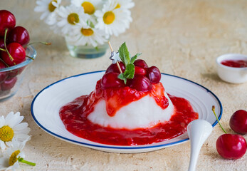 Dessert, thick jelly or pudding with cherry sauce on a white plate on a light concrete background. Dessert recipes without baking.