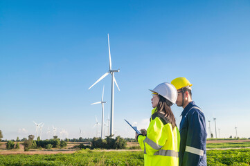 Two engineers working and holding the report at wind turbine farm Power Generator Station on...