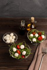 caprese salad with mozzarella and arugula in small glass bowls on a wooden table