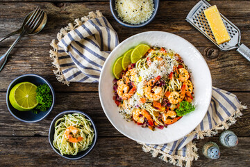 Spaghetti with prawns and parmesan on wooden table
