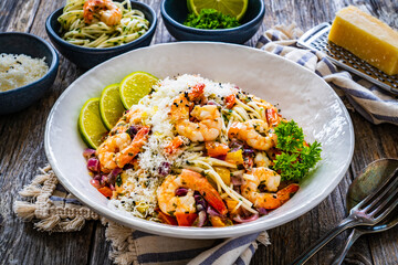 Spaghetti with prawns and parmesan on wooden table
