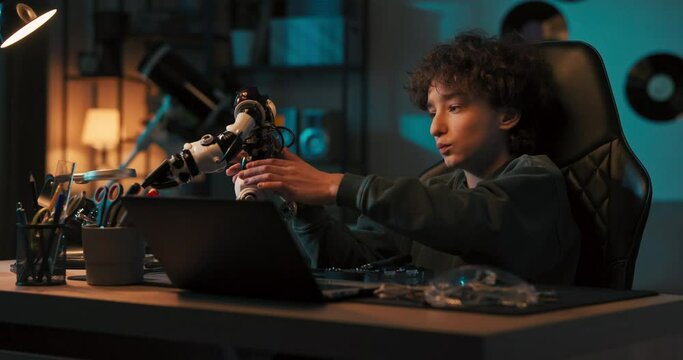 Playing with a robot in a dark room with a blue glow. Child watches toy carefully, thinks about connecting wires, repairing electronics.