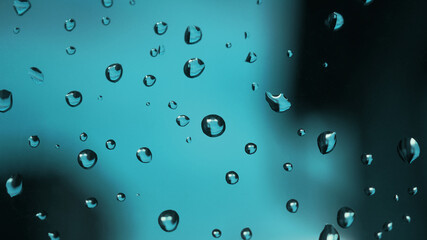 Raindrops on window glass. Turquoise tinted background. Abstract natural wallpaper. The rain is over. Macro