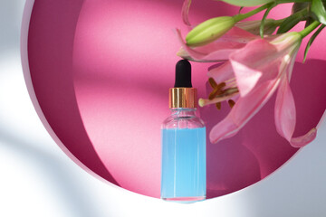 Cosmetic bottle on podium with lily flower and shadow on pink background. Face and body care spa concept. Hyaluronic acid oil, serum with collagen and peptides skin care product
