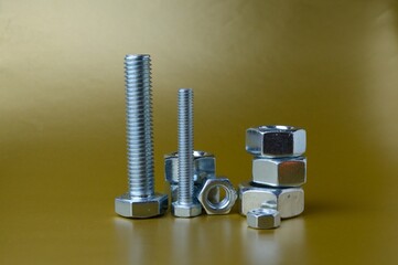composition of new nuts and bolts of different sizes on a yellow background