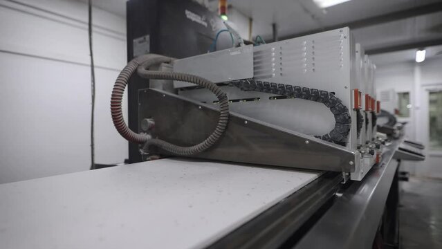 An industrial printer in a porcelain tile factory. The printer applies a pattern and texture to the board blank.