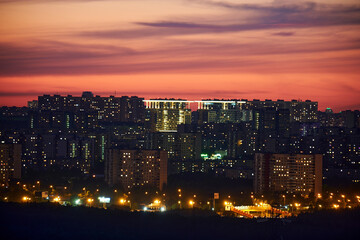 Night lights and illuminated windows of houses of the evening falling asleep city, night urban landscape