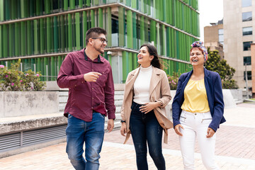 a Latin mid adult man and two women laughing while walking in the pedestrian