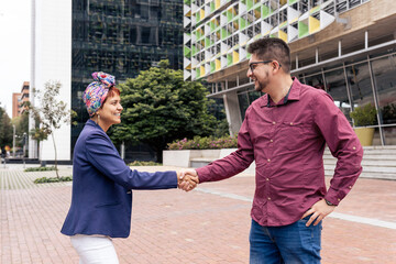 a Latin mid adult woman shaking hand with a man on the street