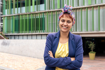 A latin woman with turban with arms crossed outdoors