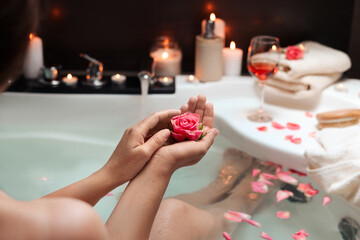 Obraz na płótnie Canvas Woman holding rose flower while taking bath, closeup. Romantic atmosphere