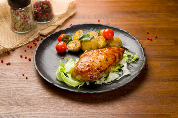 Grilled chicken Breasts with mini potatoes on black plate