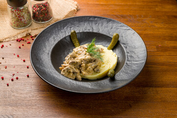 Stroganoff with beef and mashed potatoes on black plate