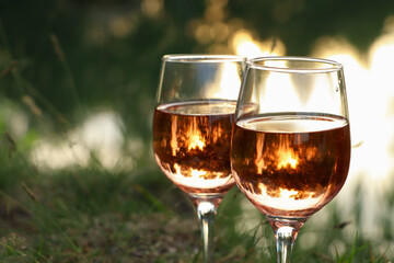 Glasses of tasty rose wine on blurred background, closeup and space for text. Picnic season