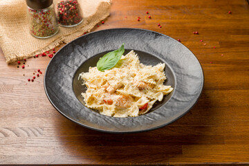 Farfalle with salmon and creamy sauce on wooden table