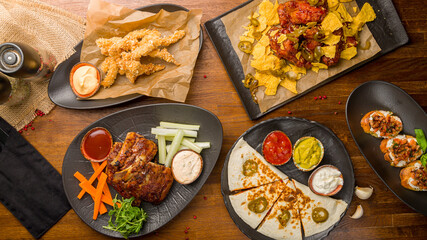 Barbecue pork ribs, quesadilla with sauces, chicken wings, chicken strips, bruschetta top view