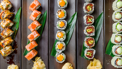set of different japan rolls with ginger, tuna roll, salmon roll, crab roll, eel dragon roll, top view on dark plates