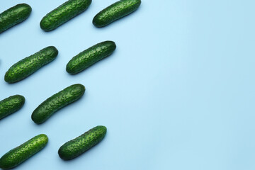 Flat lay composition with fresh ripe cucumbers on light blue background, space for text