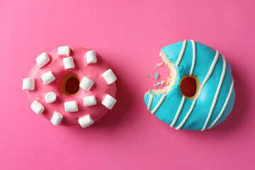 Sweet tasty glazed donuts on pink background, flat lay