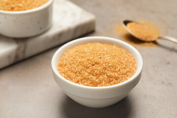 Brown sugar in bowl on grey table, closeup
