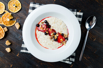 Oatmeal with strawberries and jam on white plate top view