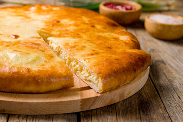 Ossetian pie with cheese on old wooden table