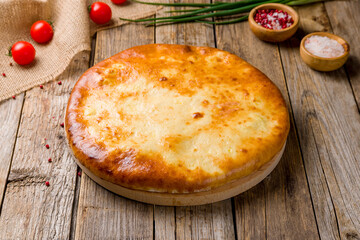 Ossetian pie with cheese on old wooden table