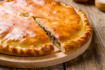 Ossetian pie with meat on wooden table macro close up