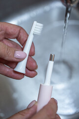 women's hands close up washing a toothbrush