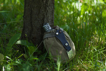 an old army flask is lying in the grass under a tree