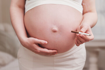 Pregnant woman with a cigarette in her hand, home living room